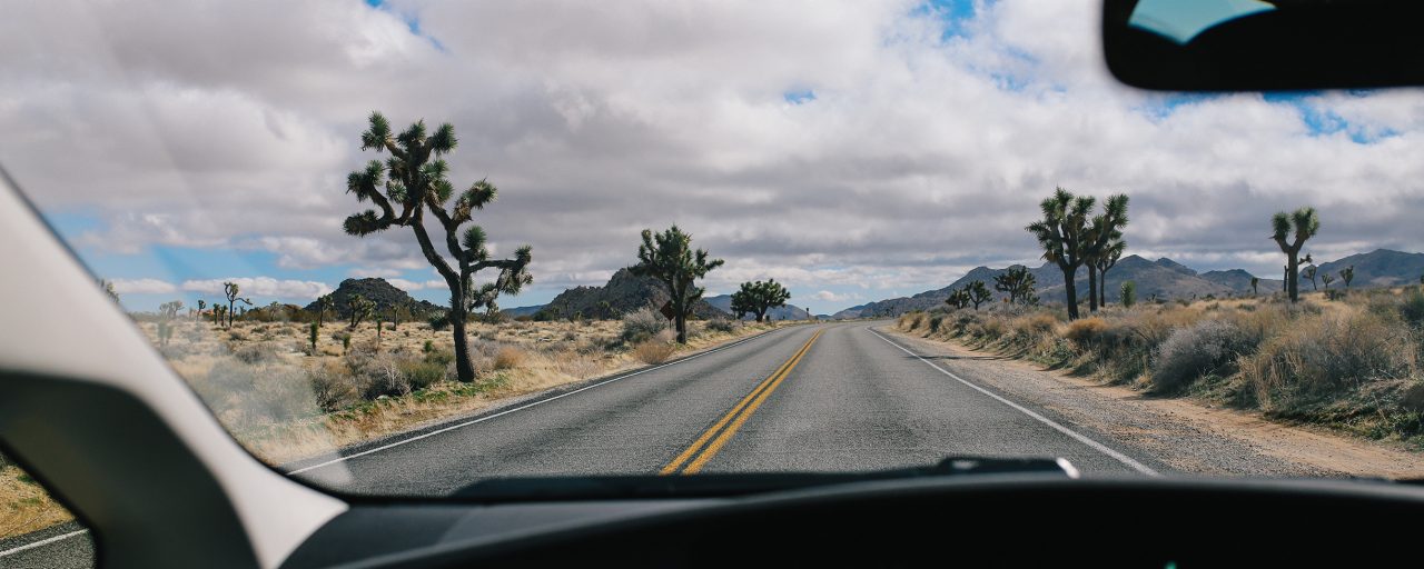 A picture of an open road on a cloudy day from inside a vehicle.